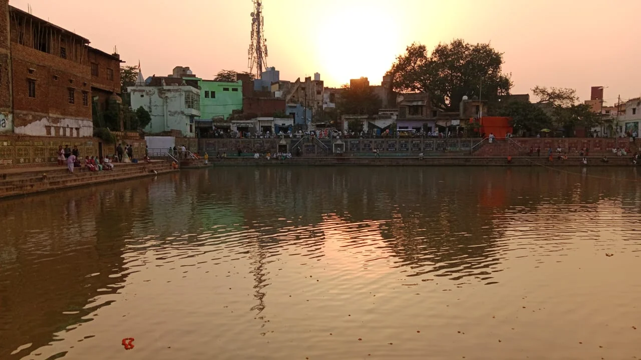 Radha-kunda in the evening with lamps and buildings around the water